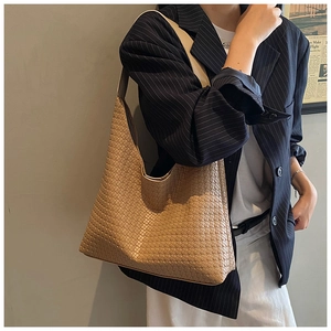 Close-up of khaki woven hobo shoulder bag texture worn by a model in a blazer