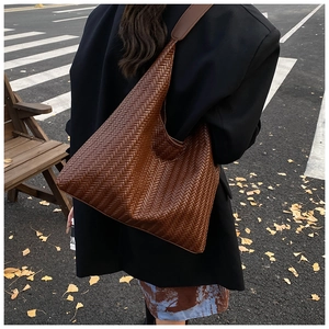 Close-up of a woven dark brown hobo bag showing texture and autumn style on street