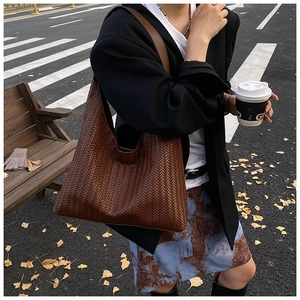 Detail of woven brown leather hobo bag featuring intricate V-pattern craftsmanship