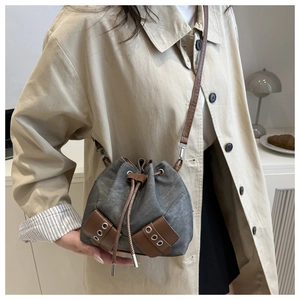 Detail of grey canvas bucket bag with drawstring closure and vintage brown leather patch
