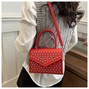 Detail view of red faux leather handbag with silver round studs and adjustable strap