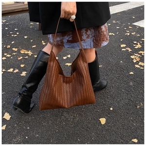 Detail showing the brown woven leather texture of a large tote bag in autumn setting