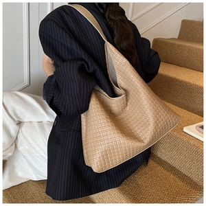 Detail of hobo tote bag with camel woven leather texture carried by a model