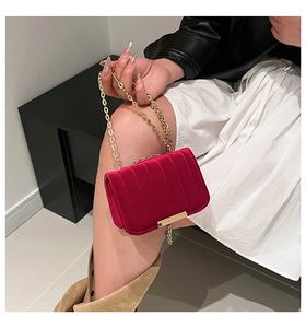 Detail of rose red velvet crossbody bag with vertical quilting and gold chain strap