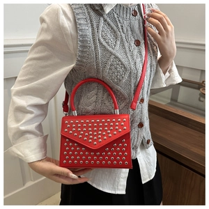 Detail of red crossbody bag with silver rivet studs and elegant top handle design