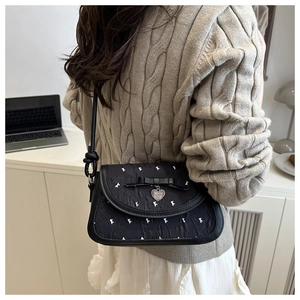 Détail du nœud noir et du pendentif cœur sur le sac bandoulière texturé avec imprimé lapin