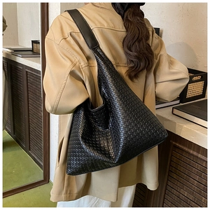 Close-up of black woven hobo tote bag featuring intricate texture and wide shoulder strap