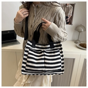 Detail view of striped canvas tote with front pockets and adjustable shoulder strap