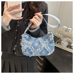 Detail of light blue denim shoulder bag with star quilting and fringe trim decoration