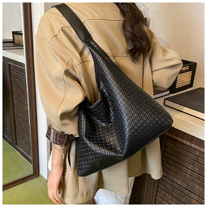 Dettaglio della trama in pelle intrecciata di una grande borsa hobo nera su modella