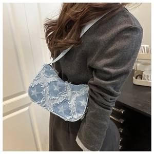 Detail of light blue denim star patterned crossbody bag with trendy frayed edge stitching