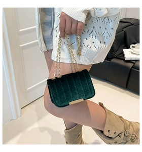 Detail of green velvet crossbody bag with gold chain strap and quilted texture