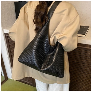 Close-up of black woven hobo tote bag texture on model shoulder for daily commute