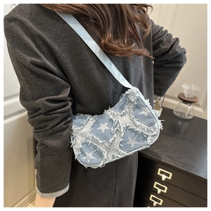 Détail du sac croissant en denim bleu clair avec motifs d'étoiles et bords effilochés