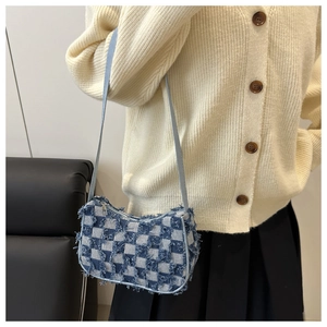 Detail of blue and white checkered denim underarm bag with unique distressed frayed edges