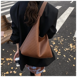Street view of a large brown woven hobo shoulder bag styled with an autumn outfit
