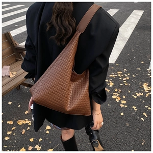 Detailed view of dark brown woven leather hobo bag worn by model in street setting