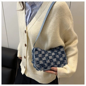 Detail view of denim crossbody bag with blue and white checkerboard pattern and frayed edges