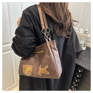Detail of coffee brown tote bag with cartoon patches and metallic chain strap detail