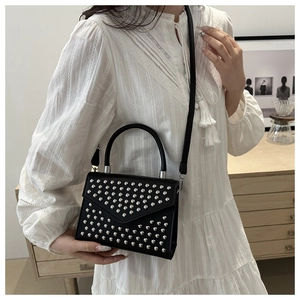 Detail of black PU leather crossbody bag featuring silver stud rivets and top handle design