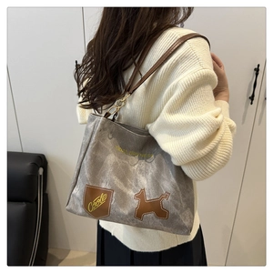 Dettaglio della borsa tote in tela tie-dye grigia con spalline in pelle e patch