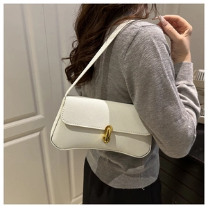 Close-up of white lychee texture shoulder bag with gold clasp worn by a model
