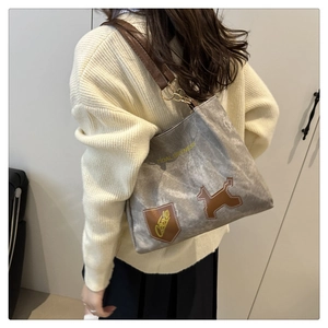 Dettaglio borsa tote grigia testurizzata con manici in pelle marrone e patch cane