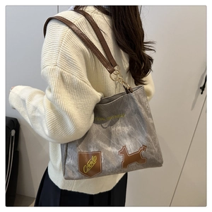 Dettaglio borsa tote in tela grigia con patch per cani in pelle e comodi spallacci marroni