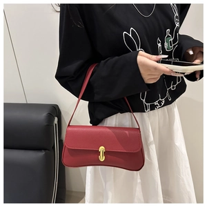 Détail du sac rouge en cuir grainé avec base en croissant et fermoir métallique doré