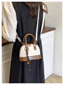 Mini shell bag in cream white and brown, shown on model with woven bell pendant detail