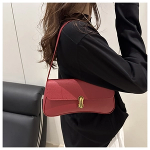 Detail of a dark red pebbled leather baguette bag with a golden oval twist lock clasp