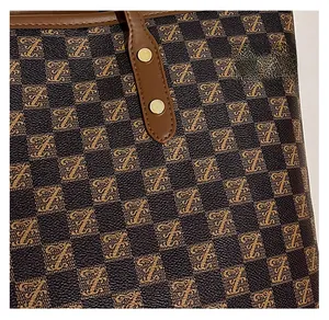 Detail shot of brown checkered tote fabric with letter F prints and golden rivets