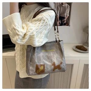 Detail of grey canvas tote bag featuring dog leather patch and artistic print design