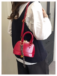 Detailed view of a red shell handbag with crocodile pattern worn with white shirt