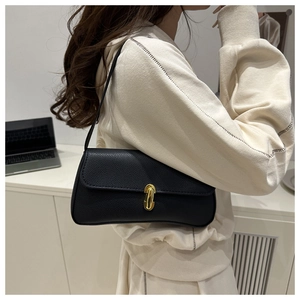 Détail d'un sac porté épaule en cuir grainé noir avec fermoir rotatif ovale en métal doré