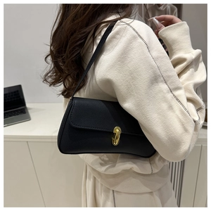 Detail of black lychee grain faux leather baguette bag with minimalist gold metal buckle