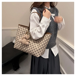 Detail of vintage tote bag with letter prints and brown leather trim and bear pendant