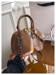 Detailed view of brown crocodile texture shell bag with sleek handles and pendant
