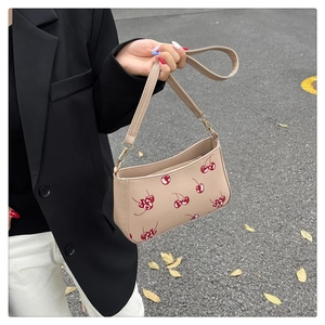 Detail of cherry print handbag showing golden zipper hardware and PU leather texture