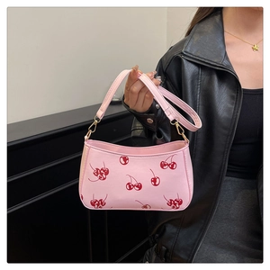 Detailed close-up of a pink cherry print handbag with adjustable shoulder strap and hardware