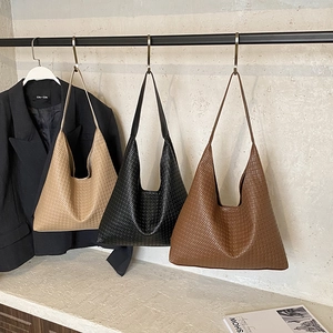 Large woven leather tote bags in beige black and brown shown in a minimalist setting