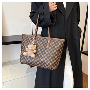 Large checkered tote bag featuring a plush bear pendant and leather handles for daily use