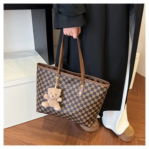 Brown checkered tote bag with a cute plush bear charm held by a person in a coat