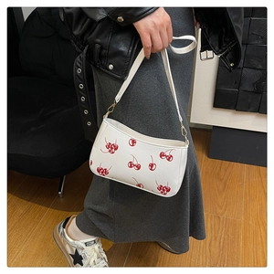 Detailed view of white cherry print handbag with glossy leather and gold hardware hooks