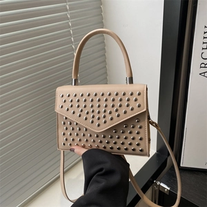 Minimalistische beige Umhängetasche mit Nieten und Tragegriff in Lifestyle-Szenerie
