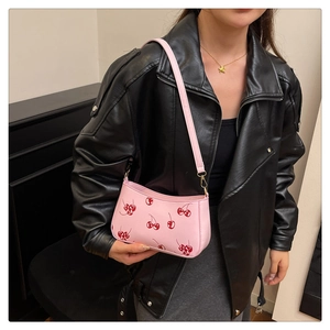 Pink leather underarm bag with red cherry prints shown on shoulder for daily fashion style