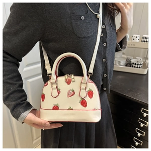 Detail of strawberry print shell bag with red edge paint and dual metal zippers