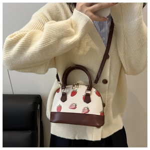 Vue détaillée du sac coquillage à motif fraise avec anses brunes et zip doré brillant