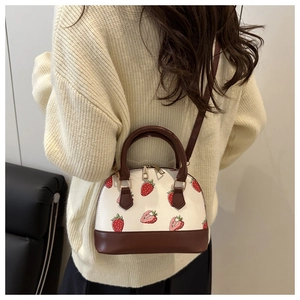 Detailed close-up of the cherry print shell bag with brown leather trim and golden zippers