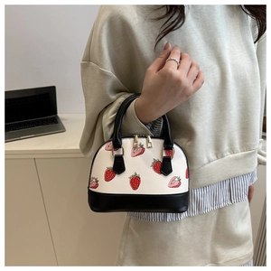 Detail of strawberry print dome handbag with gold zippers and black contrast handles